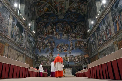 This handout picture released by the Press office shows cardinals queuing in the Sistine Chapel to swear on the Bible to never reveal the secrets of their deliberations before the start of the conclave at the Vatican on March 12, 2013. Cardinals moved into the Vatican today as the suspense mounted ahead of a secret papal election with no clear frontrunner to steer the Catholic world through troubled waters after Benedict XVI's historic resignation. The 115 cardinal electors who pick the next leader of 1.2 billion Catholics in a conclave in the Sistine Chapel will live inside the Vatican walls completely cut off from the outside world until they have made their choice. AFP PHOTO/OSSERVATORE ROMANORESTRICTED TO EDITORIAL USE - MANDATORY CREDIT AFP PHOTO/OSSERVATORE ROMANO" (Photo by OSSERVATORE ROMANO / AFP)Editoria: RELLocal: Vatican CityIndexador: -Secao: christianityFonte: OSSERVATORE ROMANO<!-- NICAID(16021229) -->