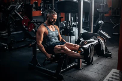 Muscular man using weights machine for legs at the gym<!-- NICAID(15546832) -->