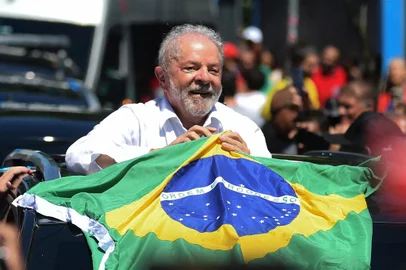 Brazilian former President (2003-2010) and candidate for the leftist Workers Party (PT) Luiz Inacio Lula da Silva holds a Brazilian flag while leaving a polling station during the presidential run-off election, in Sao Paulo, Brazil, on October 30, 2022. - After a bitterly divisive campaign and inconclusive first-round vote, Brazil elects its next president in a cliffhanger runoff between far-right incumbent Jair Bolsonaro and veteran leftist Luiz Inacio Lula da Silva. (Photo by CARL DE SOUZA / AFP)<!-- NICAID(15250258) -->