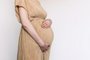 Pregnant woman in beige dress touching belly, preparing go to maternity hospital for childbirth. Pregnancy, maternity, preparation, baby expectation concept. 40 weeks of pregnancy. White backgroundGravidez, maternidade. Foto: jchizhe  / stock.adobe.comFonte: 532659101<!-- NICAID(15535477) -->