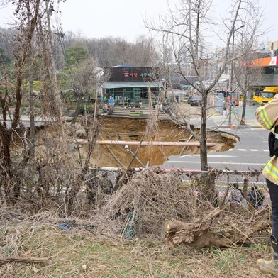 An investigator takes photos of a sinkhole outside a plant shop on a road in Seoul on March 25, 2025. One person has been killed after a massive sinkhole opened up in Seoul, the fire department said, with harrowing video footage showing the moment his vehicle was swallowed by the hole. The vast hole opened up at an intersection in the southeast of the South Korean capital during the evening rush hour around 6:30 pm (0900 GMT) on March 24. (Photo by Anthony WALLACE / AFP)Editoria: DISLocal: SeoulIndexador: ANTHONY WALLACESecao: accident (general)Fonte: AFPFotógrafo: STF<!-- NICAID(16003238) -->
