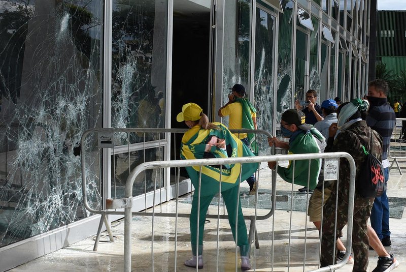Supporters of Brazilian former President Jair Bolsonaro destroy a window of the the plenary of the Supreme Court in Brasilia on January 8, 2023. - Hundreds of supporters of Brazil's far-right ex-president Jair Bolsonaro broke through police barricades and stormed into Congress, the presidential palace and the Supreme Court Sunday, in a dramatic protest against President Luiz Inacio Lula da Silva's inauguration last week. (Photo by Ton MOLINA / AFP)Editoria: WARLocal: BrasíliaIndexador: TON MOLINASecao: demonstrationFonte: AFPFotógrafo: STR<!-- NICAID(15315597) -->