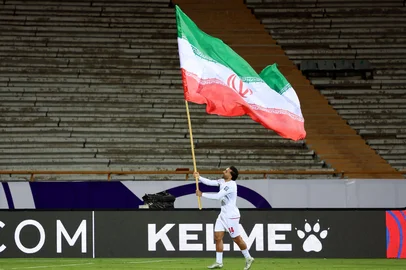 Iran's player #14 Saman Ghoddos celebrates with the Iranian flag after the FIFA World Cup 2026 Asia zone qualifiers group A football match between Iran and Uzbekistan, on March 25, 2025 in Tehran. (Photo by AFP)Editoria: SPOLocal: TehranIndexador: -Secao: soccerFonte: AFPFotógrafo: STR<!-- NICAID(16003309) -->