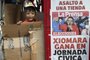 A boy plays next to a newsstand with a poster showing left-wing opposition candidate Xiomara Castro, in Tegucigalpa on November 29, 2021, a day after general elections in Honduras. - Left-wing opposition candidate Xiomara Castro took a commanding lead over the ruling party's Nasry Asfura, preliminary results showed. With just over half of votes counted, former first lady Castro had taken more than 53.5 percent with Asfura a distant second out of 13 candidates with 34 percent, according to a National Electoral Council (CNE) live count. (Photo by Orlando SIERRA / AFP)<!-- NICAID(14958229) -->