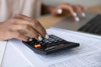 Close up of woman manage finances using laptopCrop close up of biracial woman calculate expenses expenditures on calculator machine, pay bills taxes online on computer. African American female manage budget on laptop. Saving, finance concept.Fonte: 425241195<!-- NICAID(14938560) -->