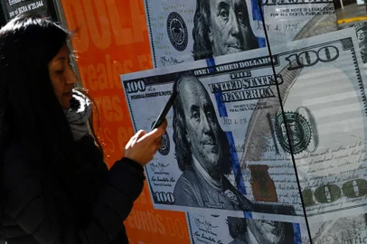 A woman walks past an image of one hundred dollar notes in Buenos Aires on August 14, 2023, a day after primary elections in Argentina. Argentine monetary authorities on August 14, 2023, devalued the peso by around 20 percent in anticipation of a market backlash to the strong performance of far-right politician Javier Milei in a presidential primary election. The Banco Nacion state bank showed the peso trading at 365.50 to the dollar, up from 298.50 on Friday. The libertarian Milei, a political outsider who has proposed dollarizing the country's battered economy, performed much better than expected in the August 13 vote, in what local media referred to as a "political tsunami." (Photo by Luis ROBAYO / AFP)Editoria: FINLocal: Buenos AiresIndexador: LUIS ROBAYOSecao: currency valuesFonte: AFPFotógrafo: STF<!-- NICAID(15509819) -->
