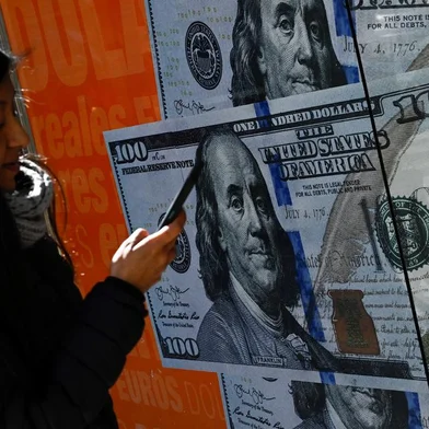 A woman walks past an image of one hundred dollar notes in Buenos Aires on August 14, 2023, a day after primary elections in Argentina. Argentine monetary authorities on August 14, 2023, devalued the peso by around 20 percent in anticipation of a market backlash to the strong performance of far-right politician Javier Milei in a presidential primary election. The Banco Nacion state bank showed the peso trading at 365.50 to the dollar, up from 298.50 on Friday. The libertarian Milei, a political outsider who has proposed dollarizing the country's battered economy, performed much better than expected in the August 13 vote, in what local media referred to as a "political tsunami." (Photo by Luis ROBAYO / AFP)Editoria: FINLocal: Buenos AiresIndexador: LUIS ROBAYOSecao: currency valuesFonte: AFPFotógrafo: STF<!-- NICAID(15509819) -->