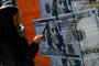A woman walks past an image of one hundred dollar notes in Buenos Aires on August 14, 2023, a day after primary elections in Argentina. Argentine monetary authorities on August 14, 2023, devalued the peso by around 20 percent in anticipation of a market backlash to the strong performance of far-right politician Javier Milei in a presidential primary election. The Banco Nacion state bank showed the peso trading at 365.50 to the dollar, up from 298.50 on Friday. The libertarian Milei, a political outsider who has proposed dollarizing the country's battered economy, performed much better than expected in the August 13 vote, in what local media referred to as a "political tsunami." (Photo by Luis ROBAYO / AFP)Editoria: FINLocal: Buenos AiresIndexador: LUIS ROBAYOSecao: currency valuesFonte: AFPFotógrafo: STF<!-- NICAID(15509819) -->