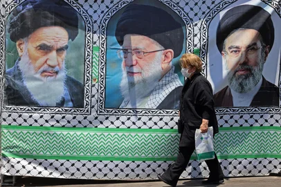 A woman walks past a banner bearing the images of the late founder of the Islamic Revolution supreme leader Ayatollah Ruhollah Khomeini (L), the late Iranian supreme leader Ali Khamenei and his son, the current supreme leader Mojtaba Khamenei (R), erected along a street at the Vanak Square in Tehran on June 10, 2026. Iran's foreign ministry said on June 10 that the United States had damaged the ongoing international diplomatic effort to end the war, after more US strikes on targets in southern Iran. (Photo by ATTA KENARE / AFP) / Editoria: WARLocal: TehranIndexador: ATTA KENARESecao: conflict (general)Fonte: AFPFotógrafo: STF<!-- NICAID(16305065) -->