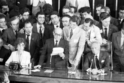 Tancredo Neves.Em 15 de janeiro de 1985, em eleição indireta realizada através do Colégio Eleitoral, os candidatos da Aliança Democrática (coligação formada pelos partidos de oposição, com exceção do PT, liderados pelo PMDB, e a Frente Liberal, integrada pelos dissidentes do PDS), Tancredo Neves e José Sarney (derrotando Maluf por 480 votos contra 180), foram eleitos, respectivamente, presidente e vice-presidente da República, pondo fim ao ciclo de presidentes militares impostos pelo regime instaurado pelo movimento político-militar de 31 de março de 1964. Tinha início, assim, uma nova era na história política do Brasil, denominada por Tancredo Neves de Nova República. No centro da foto está o deputado Ulisses Guimarães.#envelope: 28815<!-- NICAID(11345042) -->