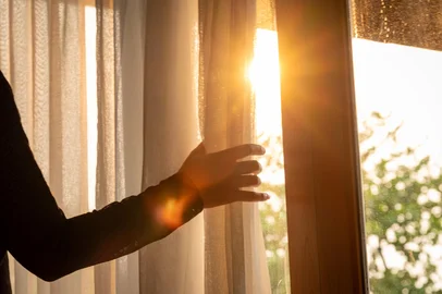 woman's hand She opened the curtains on the window. There was morning light through the window in her room, looking at the view of the mountains and trees as the sun roseFonte: 1449052446<!-- NICAID(16073343) -->