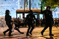 Anti-riot police officers detain a person as Paris Saint-Germain supporters celebrate after PSG won the UEFA Champions League final football match between Paris Saint-Germain (PSG) and Inter Milan held in Munich, on the Champs-Elysees avenue in Paris on May 31, 2025.