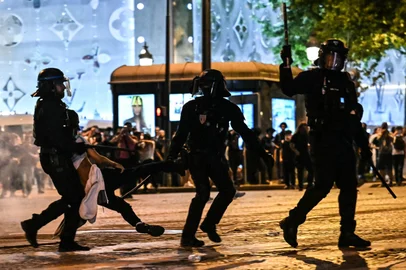 Anti-riot police officers detain a person as Paris Saint-Germain ers celebrate after PSG won the UEFA Champions League final football match between Paris Saint-Germain (PSG) and Inter Milan held in Munich, on the Champs-Elysees avenue in Paris on May 31, 2025.