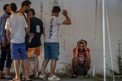 Survivors of a shipwreck stand outside a warehouse at the port in Kalamata town, on June 14, 2023, after a boat carrying dozens of migrants sank in international waters in the Ionian Sea. Greece has declared three days of mourning, the interim prime minister's office said on June 14, 2023, over a migrant boat sinking in the Ionian Sea feared to have claimed hundreds of lives. The Greek coastguard has so far recovered 79 bodies and rescued over 100, but survivors are claiming that up to 750 people were on board. (Photo by Angelos Tzortzinis / AFP)<!-- NICAID(15456697) -->