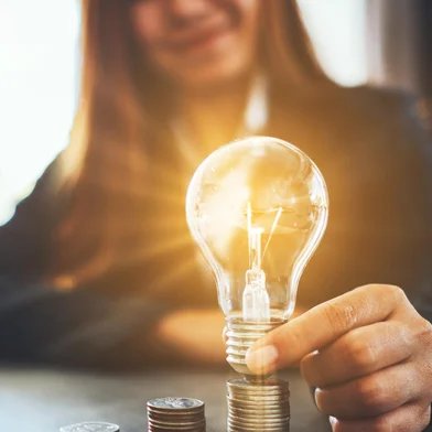 Businesswoman holding and putting lightbulb on coins stack on table for saving energy and money conceptFonte: 314277037<!-- NICAID(14411069) -->