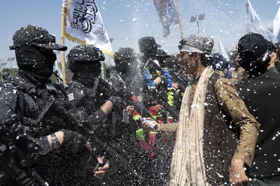 Taliban supporters celebrate next to Taliban fighters the first anniversary of the withdrawal of US-led troops from Afghanistan, at the Ahmad Shah Massoud square near the US embassy in Kabul on August 31, 2022. - The Taliban declared on August 31 a national holiday and lit up the capital with coloured lights to celebrate the first anniversary of the withdrawal of US-led troops from Afghanistan after a brutal 20-year war. (Photo by Wakil KOHSAR / AFP)Editoria: WARLocal: KabulIndexador: WAKIL KOHSARSecao: conflict (general)Fonte: AFPFotógrafo: STF<!-- NICAID(15192220) -->