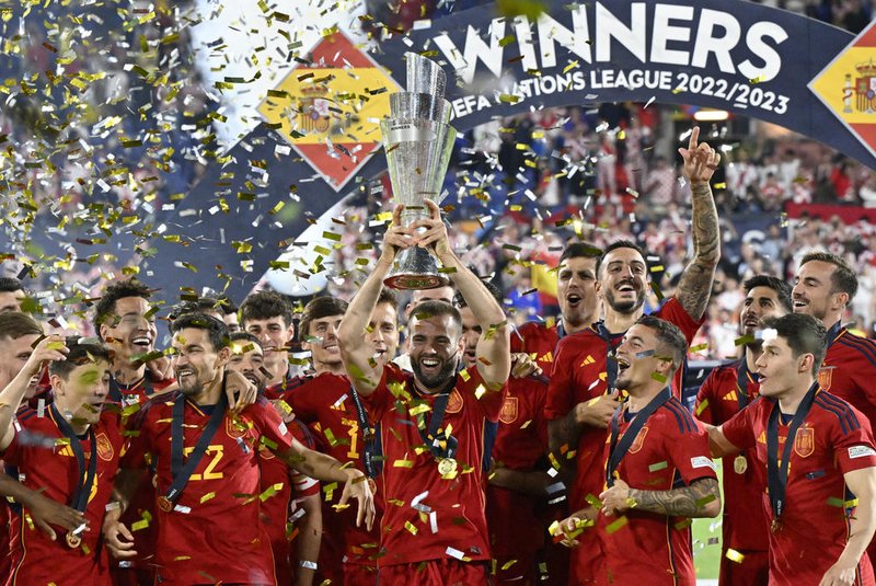Spain's defender Nacho Fernandez (C) holds the UEFA Nations League Cup as Spain's players celebrate on the podium after winning the penalty shootouts and the UEFA Nations League final football match between Croatia and Spain at the De Kuip Stadium in Rotterdam on June 18, 2023. (Photo by JOHN THYS / AFP)<!-- NICAID(15459774) -->