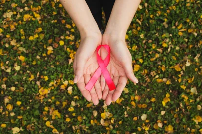 Womans hands hold pink breast cancer awareness ribbon on fall foFonte: 289892469<!-- NICAID(15227358) -->
