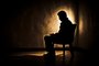 Silhueta de uma pessoa sentada na cadeira em um fundo escuro. Tristeza, depressão, saúde mental. Foto: Kodjovi / stock.adobe.comFonte: 603775008<!-- NICAID(15494537) -->