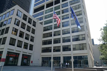 Flags fly at half-staff outside the 345 Park Avenue building, the scene of last night's deadly shootings in Midtown Manhattan in New York on July 29, 2025. A man who killed four people, then committed suicide in a New York skyscraper, may have been targeting the NFL offices there because he blamed the American football league for brain injuries he said he suffered, Mayor Eric Adams said Tuesday. The revelation that the killer, identified as 27-year-old Shane Tamura, carried a note referring to the degenerative brain disease chronic traumatic encephalopathy (CTE), offered the first possible motive for the shootings late Monday that brought central Manhattan to a standstill. (Photo by TIMOTHY A. CLARY / AFP)<!-- NICAID(16090003) -->