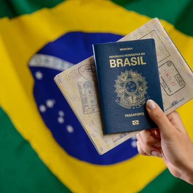 Hand holding Brazilian passport with Brazilian flag in the blurred background.Hand holding Brazilian passport with Brazilian flag in the blurred background.Indexador: Cacio Murilo de VasconcelosFonte: 524097735Fotógrafo: FotÃ³grafo<!-- NICAID(15515999) -->