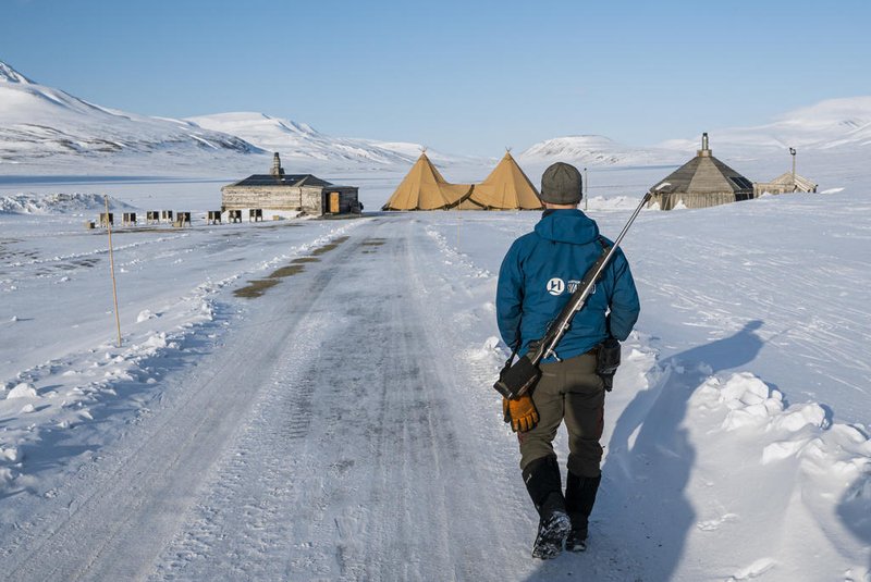 Um guia caminha com seu rifle nas costas em 4 de maio de 2022, perto de lonyearbyen, na ilha de Spitsbergen, no arquipélago de Svalbard, norte da Noruega. - Com suas cidades fantasmas e homens armados assumindo um vasto deserto, quase se poderia confundir o arquipélago de Svalbard com o Velho Oeste.Mas uma pequena força policial do Ártico nestas ilhas a meio caminho entre a Noruega e o Pólo Norte mantém fora da lei - e incomoda ursos polares - à distância. (Foto de Jonathan NACKSTRAND/AFP)<!-- NICAID(15137418) -->
