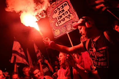A protester carries a flare during a demonstration against the Israeli government's judicial reform plan in Tel Aviv on July 27, 2023. (Photo by JACK GUEZ / AFP)<!-- NICAID(15494555) -->