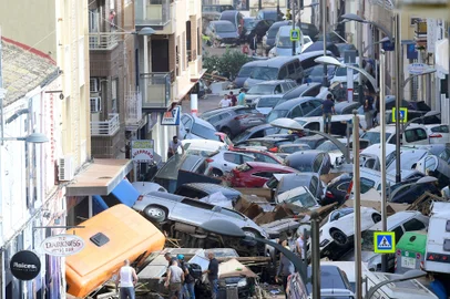 Pedestrians stand next to  piled up cars following deadly floods in Sedavi, south of Valencia, eastern Spain, on October 30, 2024. Floods triggered by torrential rains in Spain's eastern Valencia region has left at least 70 people dead, rescue services said on October 30. (Photo by Jose Jordan / AFP)Editoria: DISLocal: SedavíIndexador: JOSE JORDANSecao: floodFonte: AFPFotógrafo: STR<!-- NICAID(15903002) -->