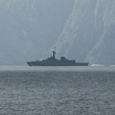 A navy vessel is seen sailing in the Strait of Hormuz, a vital waterway through which much of the world's oil and gas passes on March 1, 2026. Two ships were attacked in the Strait of Hormuz on March 1, maritime security agencies said, as Iran pressed a second day of strikes in response to US-Israeli military strikes on Iran killing it's supreme leader. (Photo by Sahar AL ATTAR / AFP)<!-- NICAID(16236644) -->
