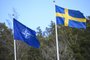 The NATO flag is raised next to a flag of Sweden (R) at a ceremony at the Musko navy base in Stockholm on March, 2024, to mark the entry of Sweden in the alliance. Sweden became the 32nd member of the military alliance. (Photo by Fredrik SANDBERG / TT News Agency / AFP) / Sweden OUT<!-- NICAID(15701948) -->