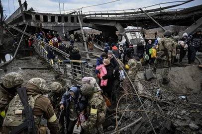 People cross a destroyed bridge as they evacuate the city of Irpin, northwest of Kyiv, during heavy shelling and bombing on March 5, 2022, 10 days after Russia launched a military in vasion on Ukraine. (Photo by Aris Messinis / AFP)<!-- NICAID(15077978) -->
