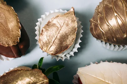 Close-up view of delicious strawberry and grape covered with white and milk chocolate decorated with leaf of edible golden chocolateFonte: 104515294<!-- NICAID(16163263) -->