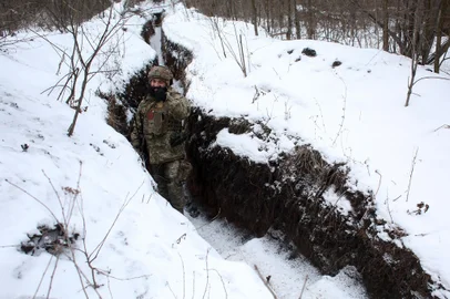 An Ukrainian Military Forces serviceman gives the thumbs-up as he stands in a snow covered trench on the frontline with the Russia-backed separatists near Zolote village, in the eastern Lugansk region, on January 21, 2022. - Ukraine's Foreign Minister Dmytro Kuleba on January 22, 2022, slammed Germany for its refusal to supply weapons to Kyiv, urging Berlin to stop "undermining unity" and "encouraging Vladimir Putin" amid fears of a Russian invasion. (Photo by Anatolii STEPANOV / AFP)<!-- NICAID(14996993) -->
