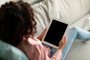 Teen african american girl holding tablet with black blank screen, using application or surfing internet at homeUso de celulares e tablets por adolescentes. Foto: Prostock-studio / stock.adobe.comFonte: 477258297<!-- NICAID(15384456) -->