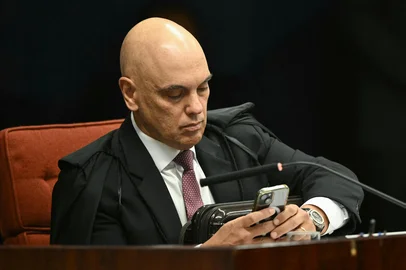 Brazil's Federal Supreme Court (STF) minister Alexandre de Moraes uses his mobile phone during the voting session to convict or acquit far-right Brazil's former President (2019-2022) Jair Bolsonaro in a coup trial at the Federal Supreme Court (STF) in Brasilia on September 11, 2025. A Brazilian judge on September 10 returned the first not-guilty vote in the coup-plotting trial of former president Jair Bolsonaro, shifting all eyes on the last two of his colleagues left to vote following two guilty findings. (Photo by EVARISTO SA / AFP)Editoria: POLLocal: BrasíliaIndexador: EVARISTO SASecao: trialsFonte: AFPFotógrafo: STF<!-- NICAID(16251554) -->