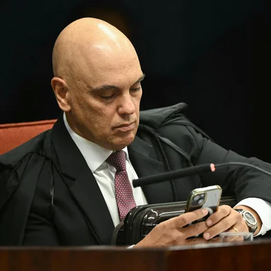 Brazil's Federal Supreme Court (STF) minister Alexandre de Moraes uses his mobile phone during the voting session to convict or acquit far-right Brazil's former President (2019-2022) Jair Bolsonaro in a coup trial at the Federal Supreme Court (STF) in Brasilia on September 11, 2025. A Brazilian judge on September 10 returned the first not-guilty vote in the coup-plotting trial of former president Jair Bolsonaro, shifting all eyes on the last two of his colleagues left to vote following two guilty findings. (Photo by EVARISTO SA / AFP)Editoria: POLLocal: BrasíliaIndexador: EVARISTO SASecao: trialsFonte: AFPFotógrafo: STF<!-- NICAID(16251554) -->