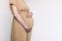 Pregnant woman in beige dress touching belly, preparing go to maternity hospital for childbirth. Pregnancy, maternity, preparation, baby expectation concept. 40 weeks of pregnancy. White backgroundGravidez, maternidade. Foto: jchizhe  / stock.adobe.comFonte: 532659101<!-- NICAID(15535477) -->