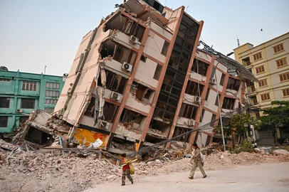 Children walk past a collapsed building in Mandalay on April 2, 2025, five days after a major earthquake struck central Myanmar. Days after a shallow 7.7-magnitude earthquake that killed more than 2,000 people, many people in Myanmar are still sleeping outdoors, either unable to return to ruined homes or afraid of further aftershocks. (Photo by AFP)<!-- NICAID(16008552) -->