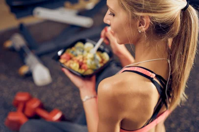 Top view of woman eating healthy food while sitting in a gym. Healthy lifestyle concept.Indexador: Milan IlicFonte: 239975148<!-- NICAID(15486571) -->