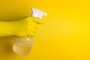 Homem com luva de proteção amarela segurando um spray de alcool líquido 70 sobre o fundo amareloIndexador: Â© Adriano SikerFonte: 362211994<!-- NICAID(15735404) -->