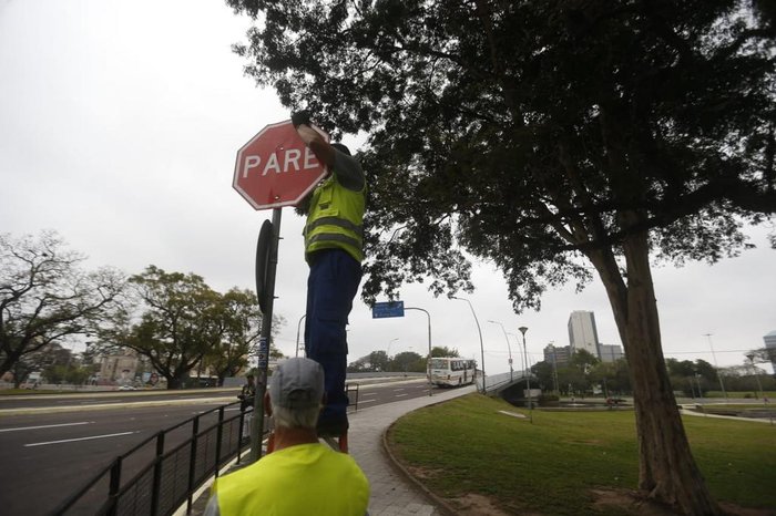 Trabalhadores consertando placas de trânsito da via