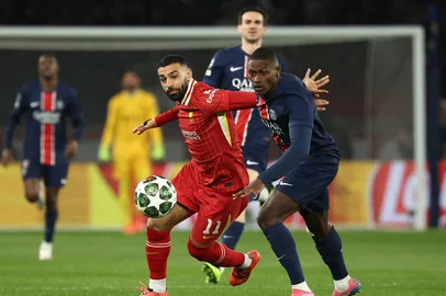Liverpool's Egyptian forward #11 Mohamed Salah (CL) and Paris Saint-Germain's Portuguese defender #25 Nuno Mendes (CR) fight for the ball during the UEFA Champions League Round of 16 first leg football match between Paris Saint-Germain (FRA) and Liverpool (ENG) at the Parc des Princes stadium in Paris on March 5, 2025. (Photo by Anne-Christine POUJOULAT / AFP)<!-- NICAID(15989343) -->