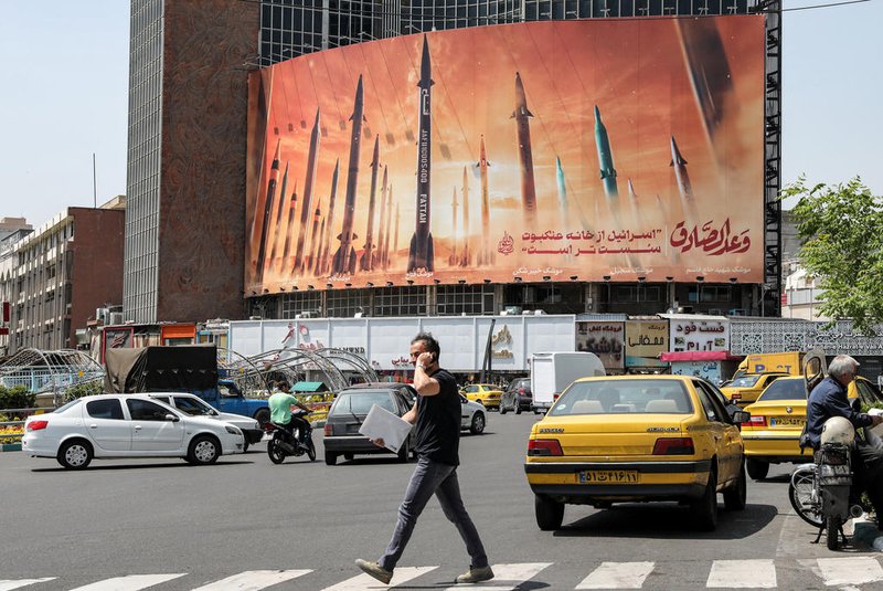 A man walks across a pedestrian crossing near a billboard depicting named Iranian ballistic missiles in service, with text in Arabic reading "the honest [person's] promise" and in Persian "Israel is weaker than a spider's web", in Valiasr Square in central Tehran on April 15, 2024. Iran on April 14 urged Israel not to retaliate militarily to an unprecedented attack overnight, which Tehran presented as a justified response to a deadly strike on its consulate building in Damascus. (Photo by ATTA KENARE / AFP)Editoria: WARLocal: TehranIndexador: ATTA KENARESecao: conflict (general)Fonte: AFPFotógrafo: STF<!-- NICAID(15735127) -->