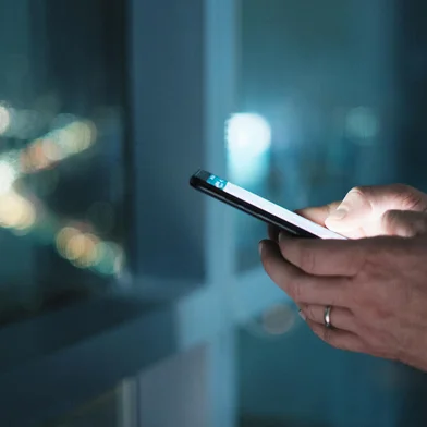 Hands Of Business Man Typing Text Message On PhoneMan working in modern office late at night. Busy caucasian manager at work texting on cell phone, with city and traffic lights in background. Close-up of hands holding smartphoneFonte: 243193396<!-- NICAID(14839125) -->