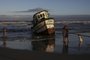 Imbé, RS, Brasil, 18-02-2024: O barco pesqueiro Litoral segue na beira da praia de Imbé, dias após naufragar na Barra de Tramandaí. Embarcação chama a atenção de veranistas, que se aproximam para fotos. Foto: Mateus Bruxel / Agência RBSIndexador: Mateus Bruxel<!-- NICAID(15682902) -->