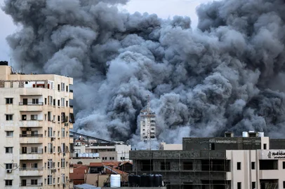EDITORS NOTE: Graphic content / A plume of smoke rises above buildings in Gaza City on October 7, 2023 during an Israeli air strike. At least 70 people were reported killed in Israel, while Gaza authorities released a death toll of 198 in the bloodiest escalation in the wider conflict since May 2021, with hundreds more wounded on both sides. (Photo by MAHMUD HAMS / AFP)<!-- NICAID(15563079) -->