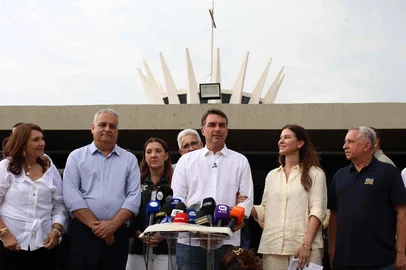 Brazil's right-wing Senator and presidential candidate for the Liberal Party (PL) Flavio Bolsonaro (C) speaks to the media alongside his wife Fernanda Bolsonaro (2-R) following a mass marking the celebration of Brazil's patron saint, Our Lady of Aparecida, at the Metropolitan Cathedral of Brasilia in Brasilia, Brazil, on October 12, 2026. (Photo by Sergio LIMA / AFP)<!-- NICAID(16385639) -->