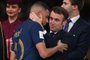 France's forward #10 Kylian Mbappe is greeted by French President Emmanuel Macron on the podium after receiving the silver medal during the Qatar 2022 World Cup trophy ceremony after losing the football final match between Argentina and France at Lusail Stadium in Lusail, north of Doha on December 18, 2022. - Argentina won in the penalty shoot-out. (Photo by FRANCK FIFE / AFP)<!-- NICAID(15298789) -->