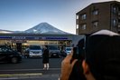 This photo taken on January 1, 2024 shows a tourist posing in front of a convenience store with Mount Fuji in the background, in the town of Fujikawaguchiko, Yamanashi prefecture. A huge black barrier to block Mount Fuji from view will be installed in a popular photo spot by Japanese authorities exasperated by crowds of badly behaved foreign tourists, it was reported on April 26, 2024. (Photo by Philip FONG / AFP)Editoria: LIFLocal: FujikawaguchikoIndexador: PHILIP FONGSecao: mountainsFonte: AFPFotógrafo: STF<!-- NICAID(15745823) -->