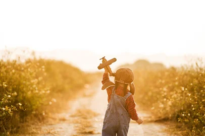dashu83 / stock.adobe.com Child pilot aviator with airplane dreams of traveling in summer in nature at sunset<!-- NICAID(16385422) -->